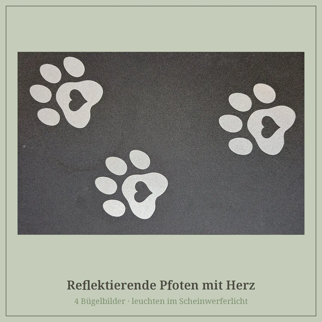 Drei reflektierende Pfoten mit Herz auf dunklem Stoff